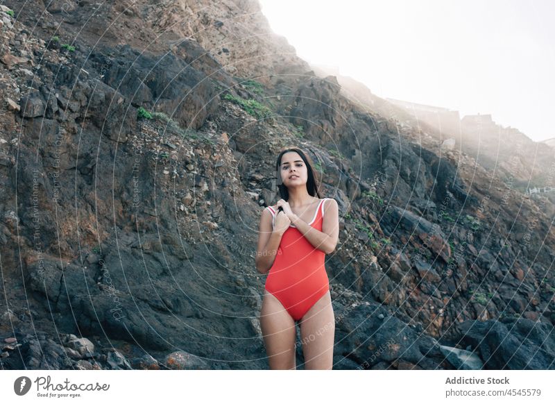 Woman in swimsuit on rocky cliff woman swimwear coast shore coastal nature adventure pastime trip stone formation leisure environment seaside beach seashore