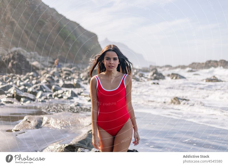 Woman in swimsuit near waving sea woman water swimwear coast shore coastal nature adventure pastime trip formation leisure environment seaside beach seashore