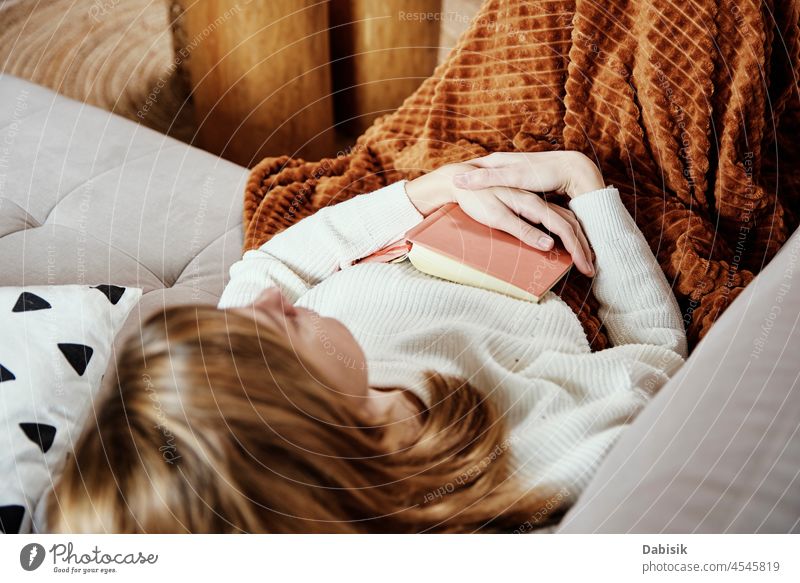 Young woman lying in bed while reading a book - a Royalty Free Stock Photo  from Photocase