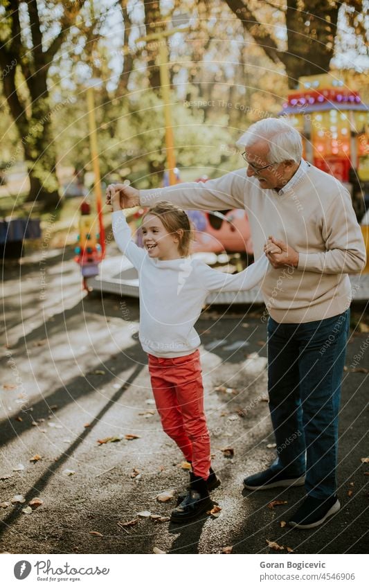 Grandfather having fun with his little granddaughter in the amusement park kid holiday grandfather man girl senior child love caucasian elderly weekend