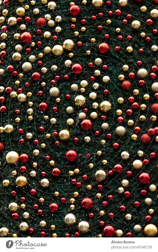 Texture of Christmas balls hanging on a huge background of green leaves representing a Christmas tree, Madrid, Spain Christmas decoration branches golden balls