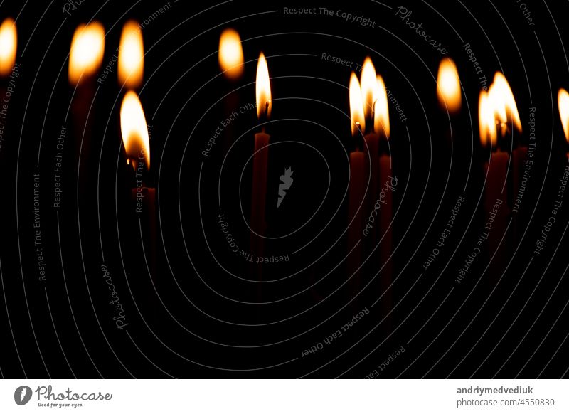 close up a lot of burning candles isolated on black background. candlelight flame fire night glow church religion christmas dark praying glowing religious