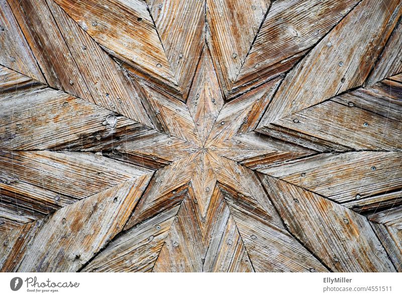 Star-shaped decoration on an old weathered wooden door. background Wood Stars stellar Weathered Old Art Craft (trade) Detail Close-up Brown