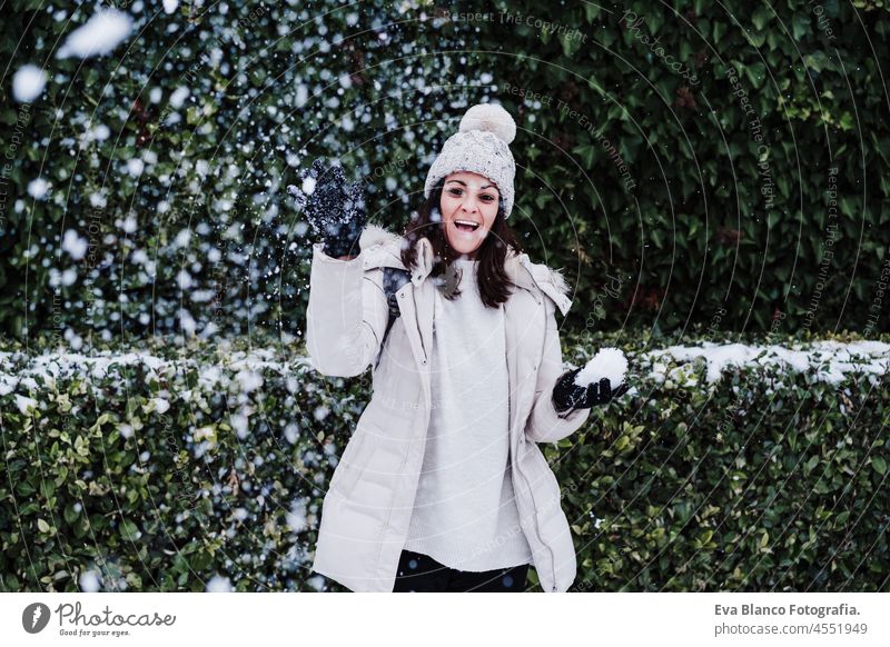 playful caucasian young woman playing outdoors with snow and snowflakes, throwing snow ball to camera, fun and winter lifestyle park mountain snow flake snowing