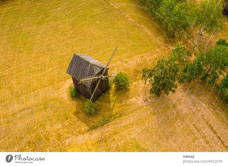 Close up old wooden mill blades. Bright sky of the setting sun. Small crossroads in the background. Aerial above aerial shot aerovista architecture attraction