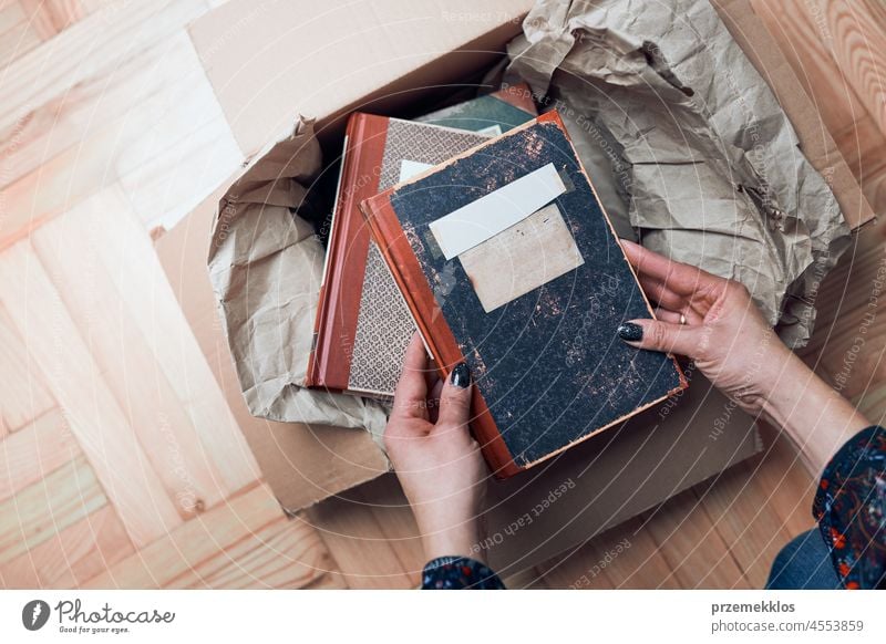 Woman taking books out of cardboox. Unpacking parcel unpacking taking out package cardboard box shipping open woman client female new delivery send commerce