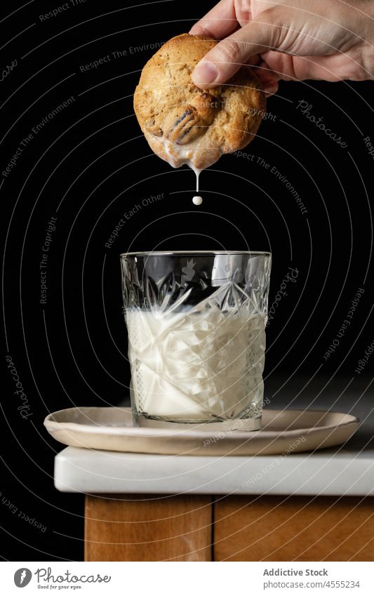 Unrecognizable person dipping cookie into milk sweet dessert pastry baked homemade confection culinary food tasty table treat yummy bakery fresh glass delicious