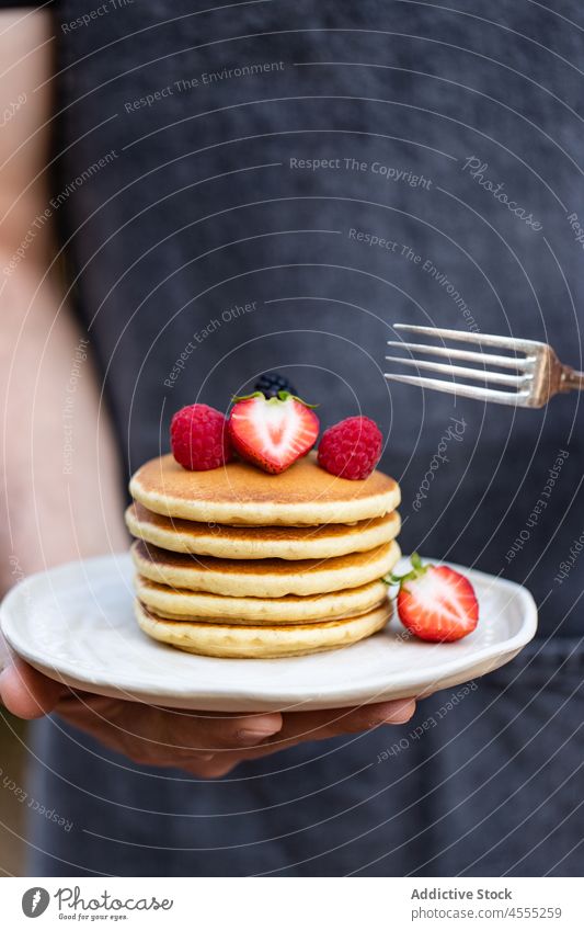 Crop person with delicious pancakes dessert food sweet strawberry raspberry tasty yummy stack carry plate organic breakfast serve fresh appetizing portion snack