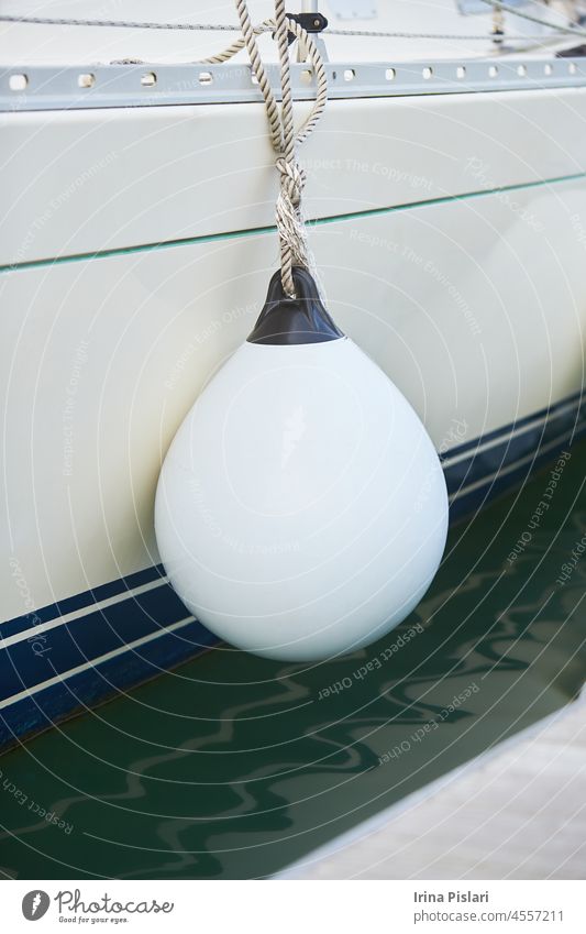 White fenders suspended between a boat and dockside for protection. Maritime fenders blue board boating bouy bumper buoy closeup coast detail equipment exterior