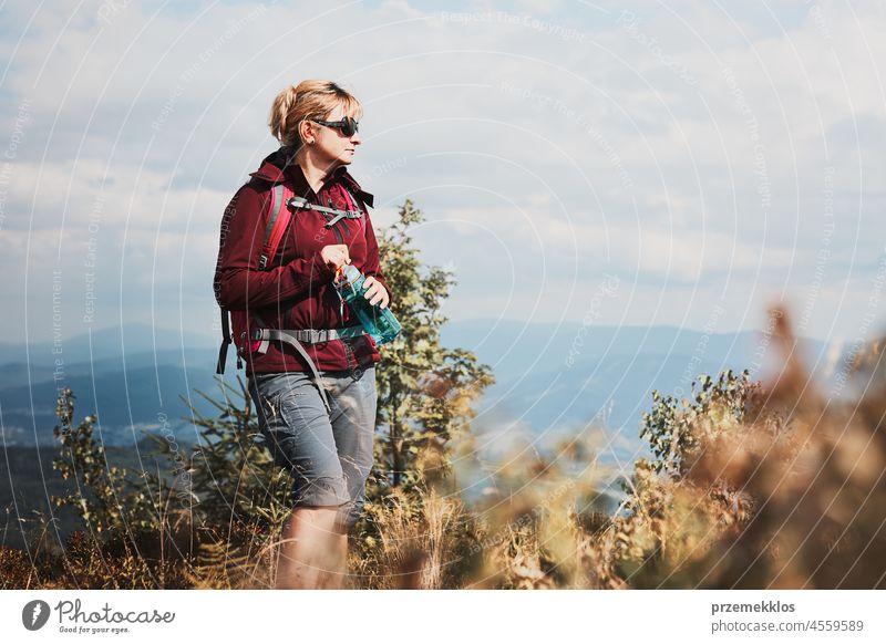 Woman with backpack hiking in mountains, spending summer vacation