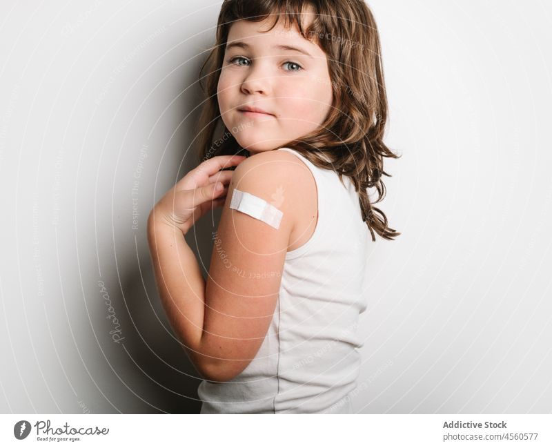 Serious vaccinated girl with band aid on arm schoolgirl bandage vaccine protect virus vaccination jab happy smile shot safety health care medical healthy