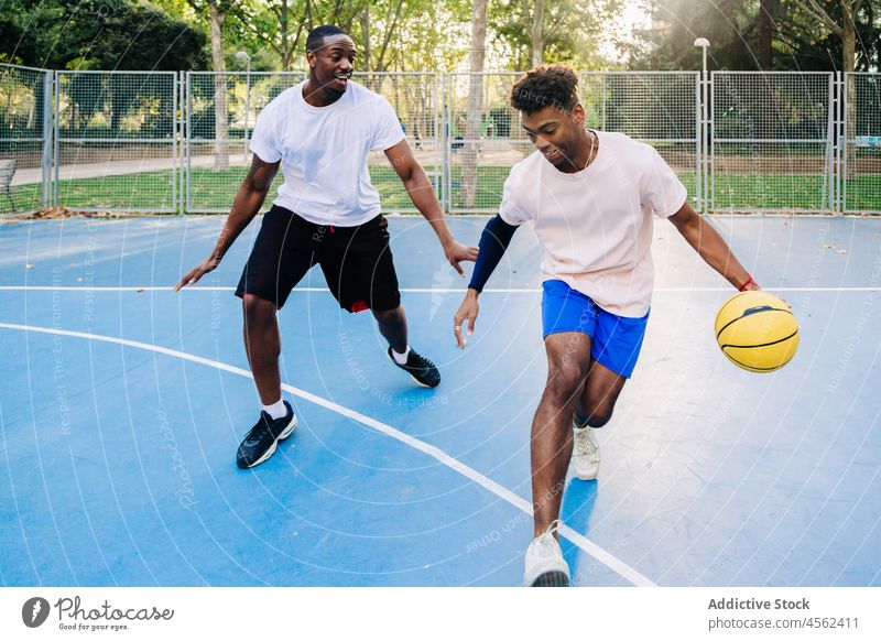 Black ethnic athletes running with ball while playing basketball men friend sports ground player together game court team training activity friendship dynamic