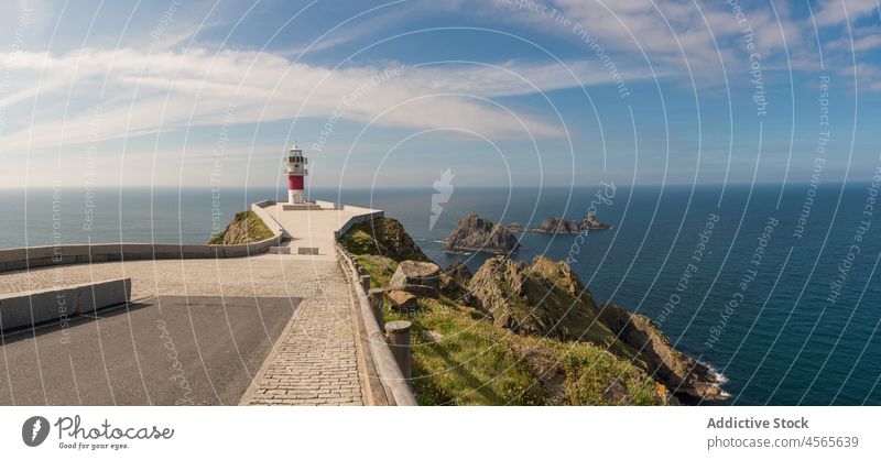 Lighthouse on rocky cliff near calm sea in sunny day lighthouse seascape seashore picturesque scenic spectacular coast ocean spain galicia seaside coastline