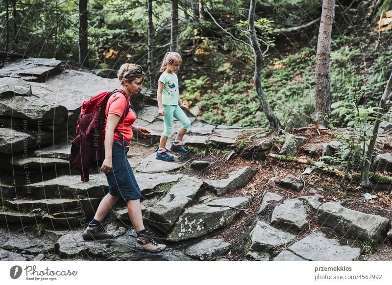 Family trip in mountains. Mother with little girl walking on path