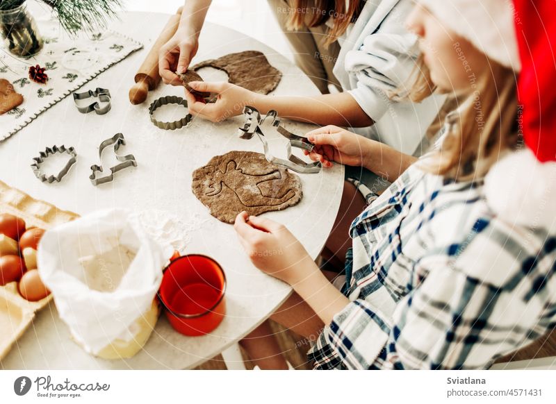 Two sisters are preparing gingerbread cookies for Christmas. Preparation for Christmas and New Year, Christmas cookies. Side view christmas kitchen dough baking