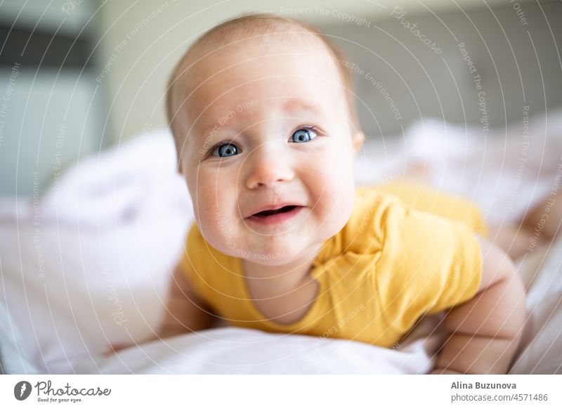 Caucasian blonde baby seven months old lying on bed at home. Kid wearing cute clothing yellow color newborn infant Illuminating child ultimate gray kid