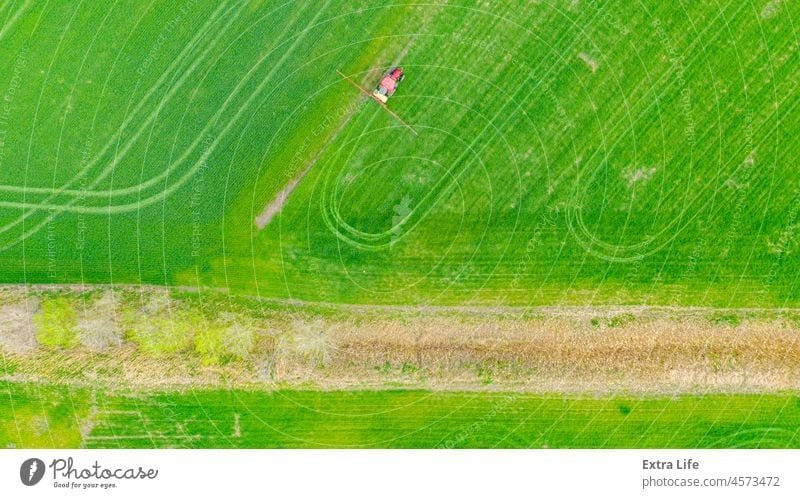 Aerial view on tractor as spraying field with young cereal culture using sprayer, herbicide and pesticide Above Aerosol Agricultural Agriculture Arable Barley