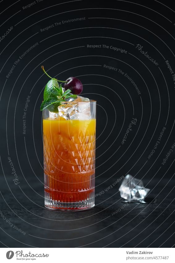 Orange juice with mint and cherry ice in a glass on a dark background. Low key alcohol alcoholic alcoholic cocktail aperitif aperol spritz bar beverage cafe