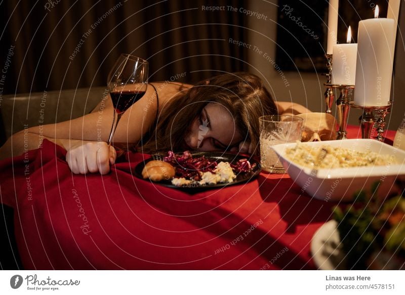 A bit too much food and maybe wine for this gorgeous brunette girl. A delicious meal and a fine glass of red wine. A sleeping beauty next to candlelight. lunch