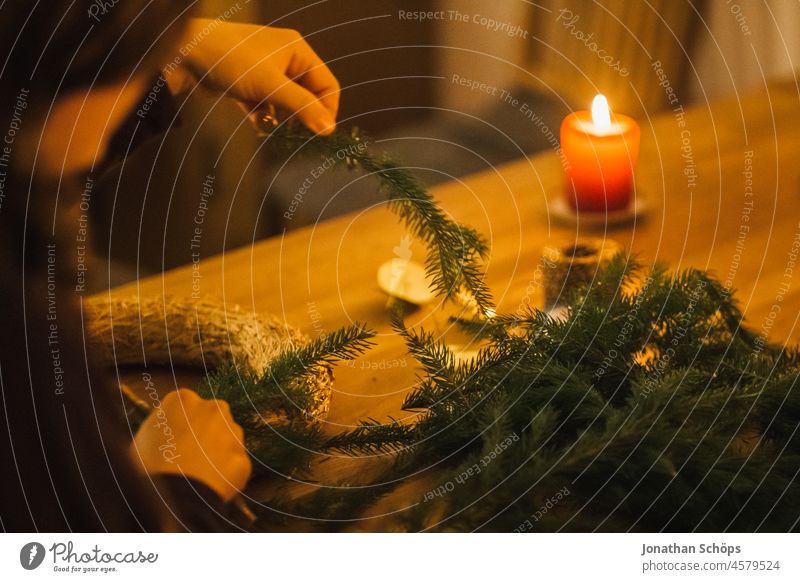 Woman making Advent wreath from brushwood at home table by candlelight Christmas wreath Wreath Handicraft Bond do it oneself DIY Christmas & Advent Table