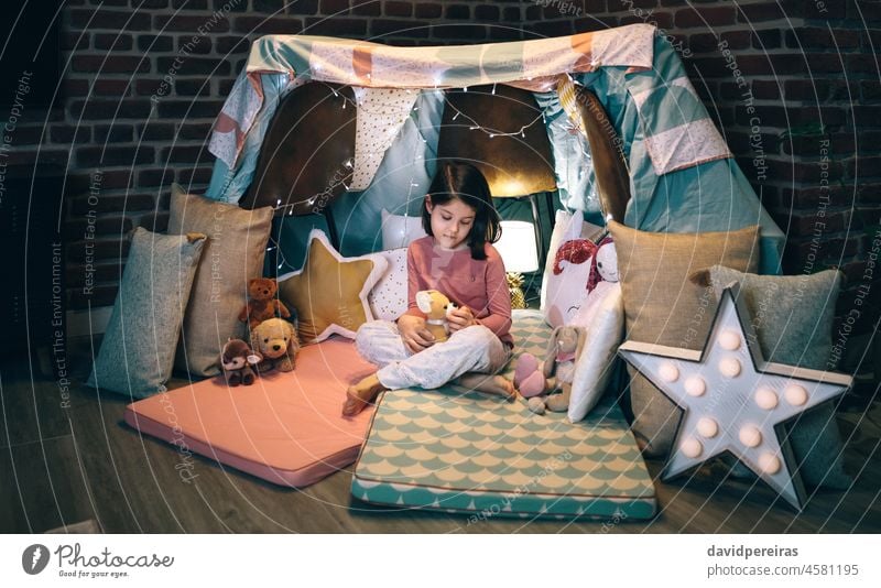 Girl playing with stuffed animals in a teepee girl thoughtful melancholic sad cute teddy night child kid childhood female toy beautiful little people person