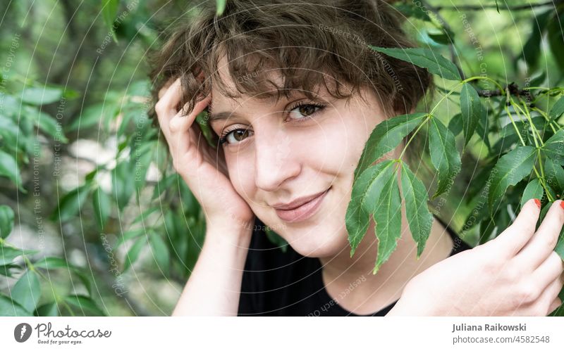 beautiful woman in nature with leaves in front of face Life Smiling Esthetic Emotions Environmental protection closeness to nature Tree Joie de vivre (Vitality)