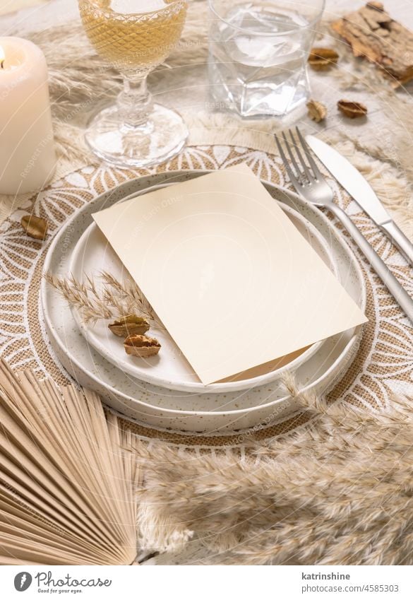 Boho Wedding Table place with Blank card on plate near dried plants, mockup bohemian paper wedding table place boho pampas grass tropical palm leaves beige