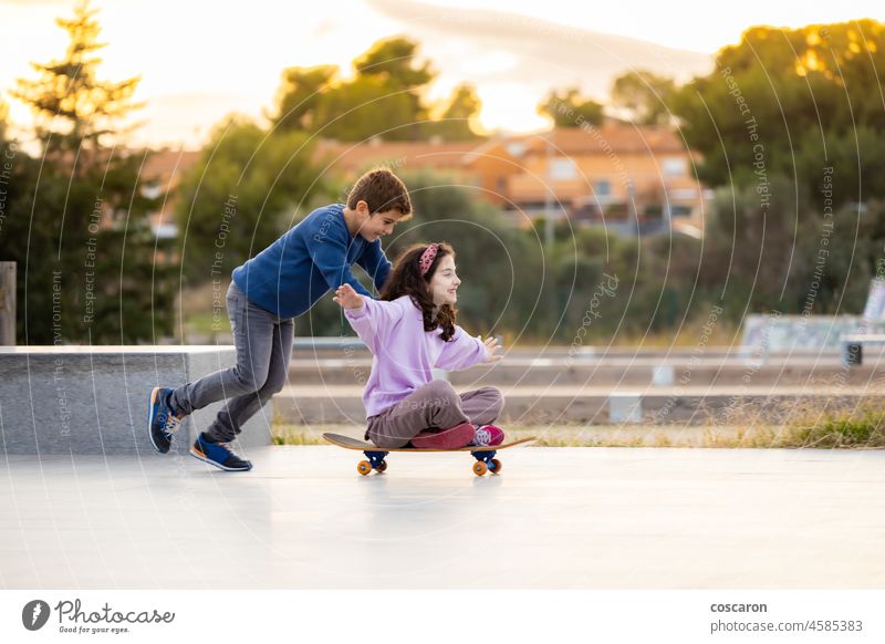 Two friends playing with a skate board boy brotherhood brothers caucasian child childhood city cooperating cute emotional enjoyment excitement female