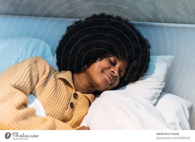 Black woman sleeping on bed at home rest nap relax eyes closed comfort bedroom female black african american afro peaceful young calm curly hair asleep lying