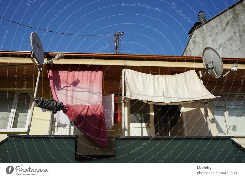 Balcony with cloths as sunshades and satellite dishes in summer with blue sky and sunshine in Adapazari in the province of Sakarya in Turkey Summer Sky