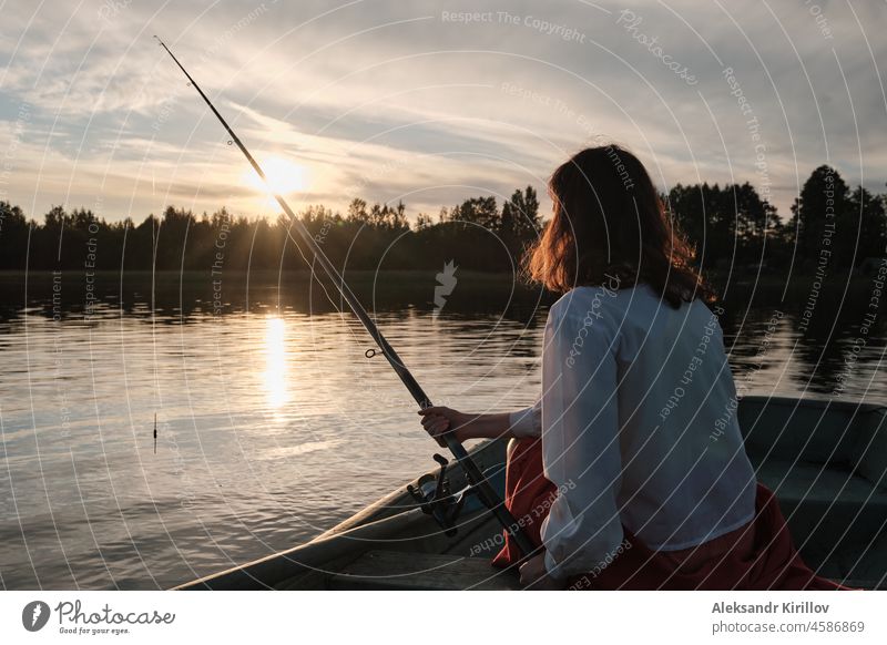 Girl is fishing with a fishing rod. Girl is sitting in the boat fisherwoman ship trap offshore spinning catch net stream enjoyment flow recreation reel