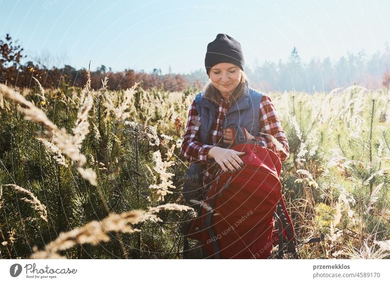 Young woman enjoying trip in mountains. Woman standing on trail. Woman with backpack hiking through tall grass along path in mountains adventure travel summer