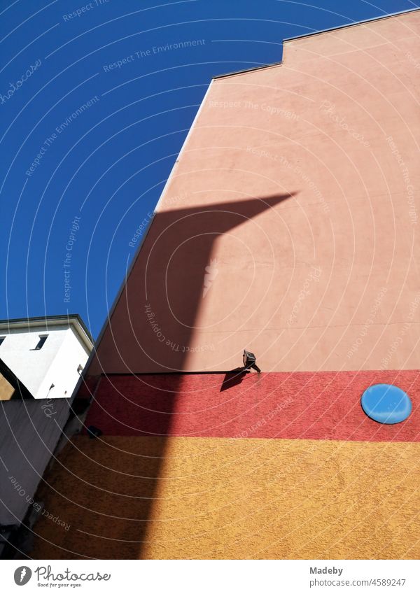 Facade in apricot and beige with blue dots and red stripes under a bright blue sky in summer sunshine in the north end of Frankfurt am Main in Hesse, Germany