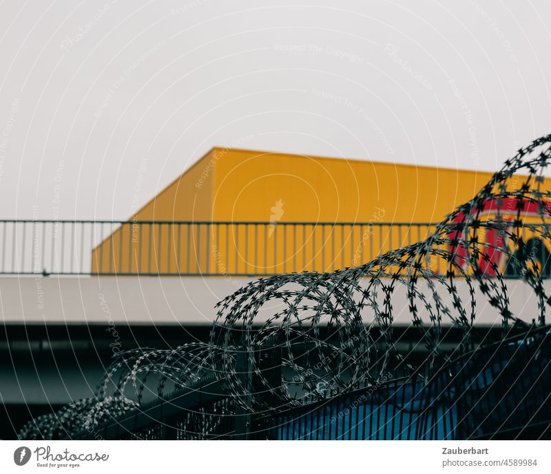 Barbed wire in front of bridge and cuboid yellow warehouse Bridge Territory Yellow Cuboid Depot Nato wire Border Barrier Wire Fence Safety Protection Threat