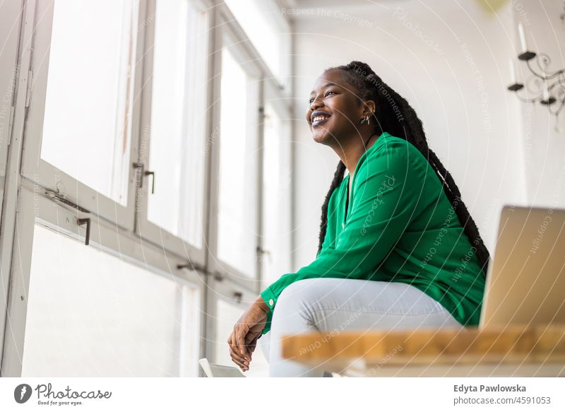 Portrait of a smiling creative woman in a modern loft office black millennials hipster indoors window natural adult one attractive successful people confident