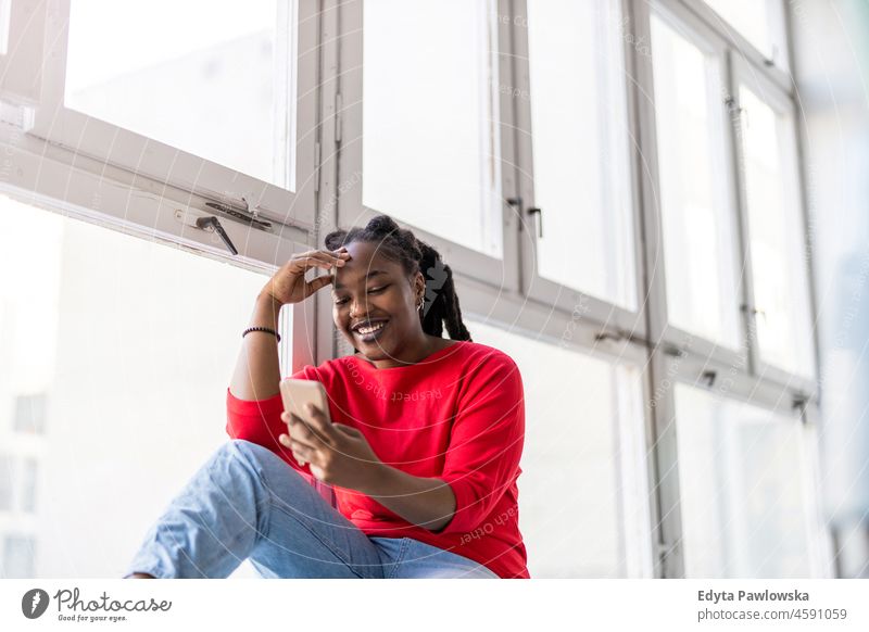 Young woman using smartphone in loft office black millennials hipster indoors window natural adult attractive successful people confident person beautiful young