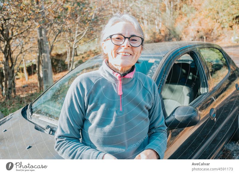 Portrait of a happy smiling senior woman outside car learning to drive a car. Safety drive. Learning new hobby, habit and skill for this new year. Elderly person approving the driving license.