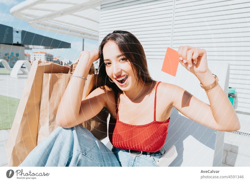 Young african woman holding a credit card blanck space shopping outdoors with copy space. Happy,trendy hipster girl ordering food online,booking tickets during a sunny day.Trendy young people surprise