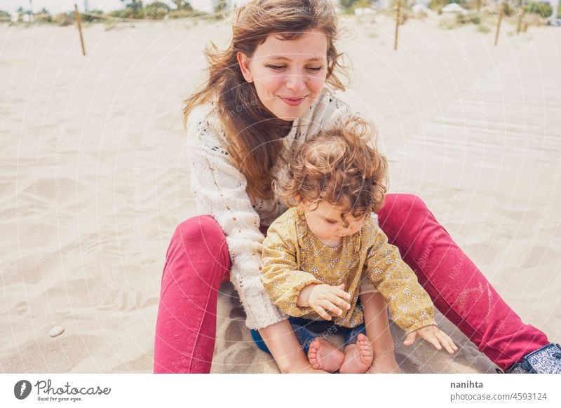 Young mom playing with her baby in the sand family motherhood vacation happiness happy playful fun funny childhood parenthood parenting casual candid life