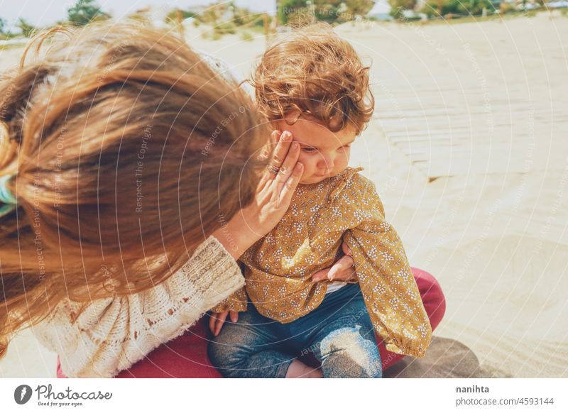 Young mom playing with her baby in the sand family motherhood vacation happiness happy playful fun funny childhood parenthood parenting casual candid life