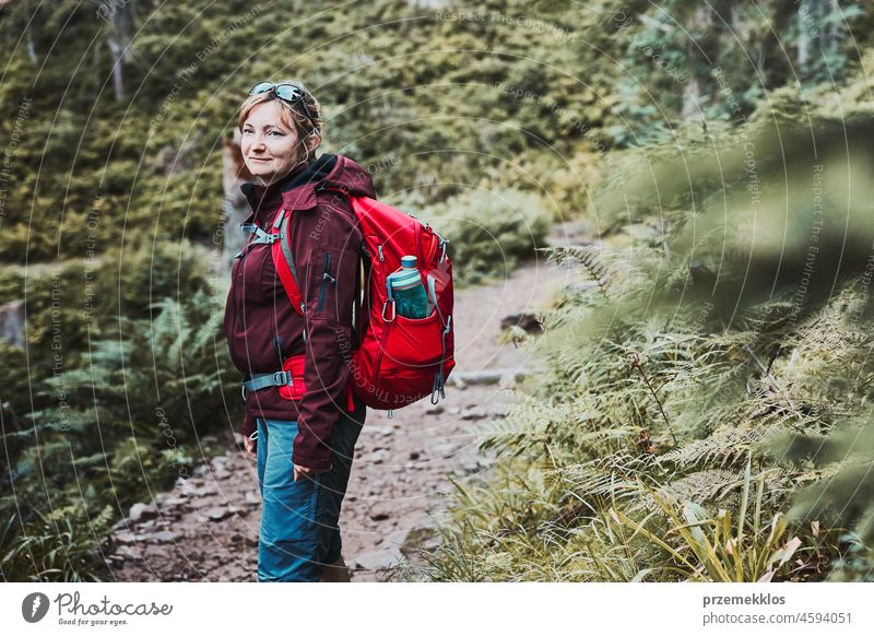 Woman with backpack hiking in mountains, spending summer vacation
