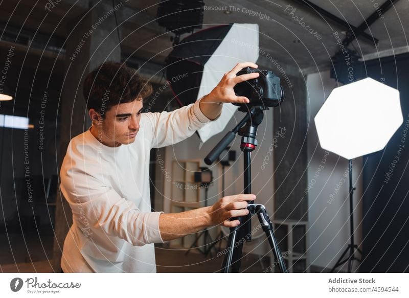 Man setting photo camera on tripod in studio man photographer photo session professional photography take photo lens equipment male light octabox device work