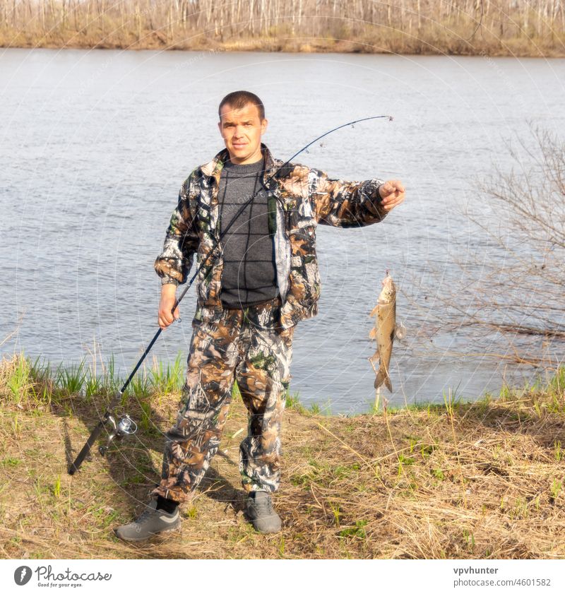 A Fisherman with Fishing Rods, a Spinning Reel on the River Bank