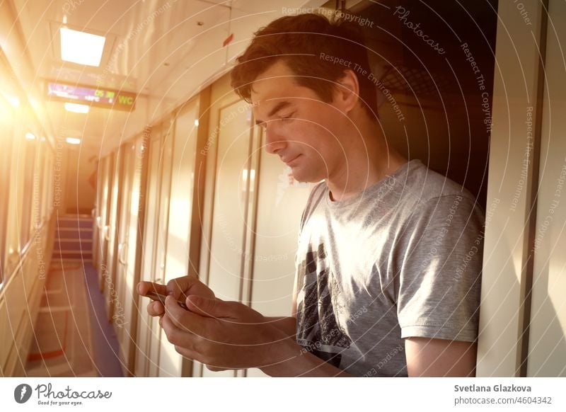 Solo travel Adult man travels alone by train. He stands in an empty train carriage and texting on a phone. Using smartphone technology online New normal male