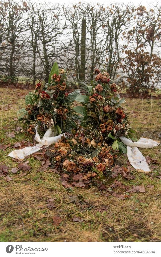 Dead man's wreath withered on a cemetery in the Hunsrück region Cemetery Grave Autumn Winter Death dead Wreath Bow Banderole roses Faded Shriveled dried leaf