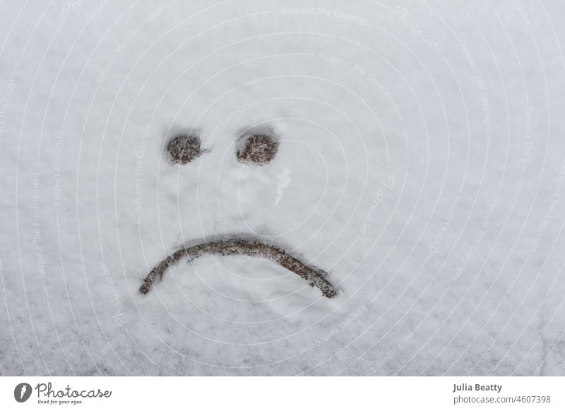 Sad face drawn on the ground after a light snowfall; dreaming of summer sad face emoji frown frown face sketch drawing simple line drawing first snow dusting
