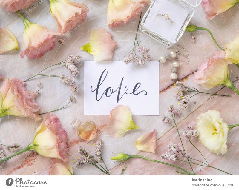 Card with the text LOVE surrounded by pink flowers love card lettering LISIANTHUS Flowers top view Marriage handwritten Marble table paper quote message craft