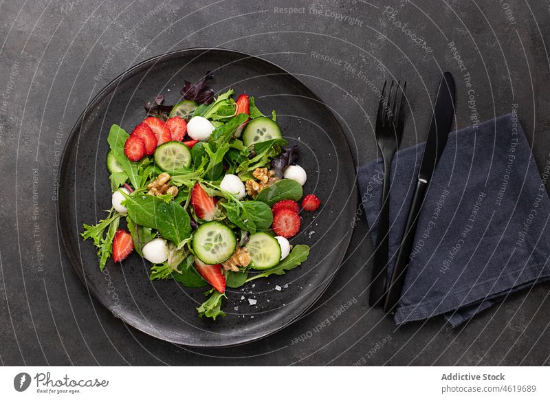 Table with a strawberry salad next to some cutlery appetizing mix top view mozzarella nut healthy dark vegetable dish colorful flat lay above leaves served