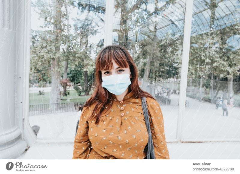 Young woman using a face mask protecting her from covid and other virus, flu and health problems. Outdoors protection during a pandemic. Hipster and modern style, young university student.