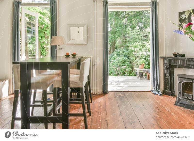 Interior of cozy dining room in cottage viewed to backyard window apartment fireplace interior comfort furniture spacious wooden style home modern chair garden